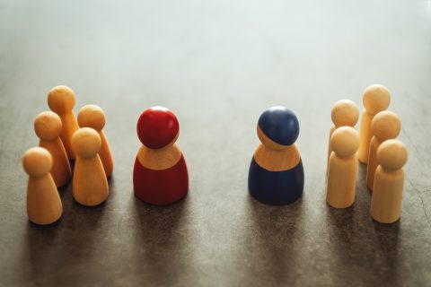 two leaders of teams of wooden play people facing off